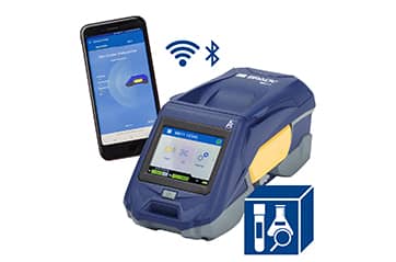 A Brady M611 label printer shown alongside a mobile phone connecting to it via bluetooth or wi-fi and with an icon indicating the printer comes with laboratory labeling software