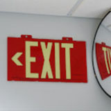 A BradyGlo exit sign. The letters and arrow glow in the dark so that the text is visible even when there is no power source.