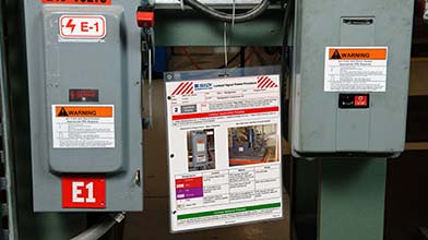 Industrial breaker boxes with a procedure checklist posted next to them.