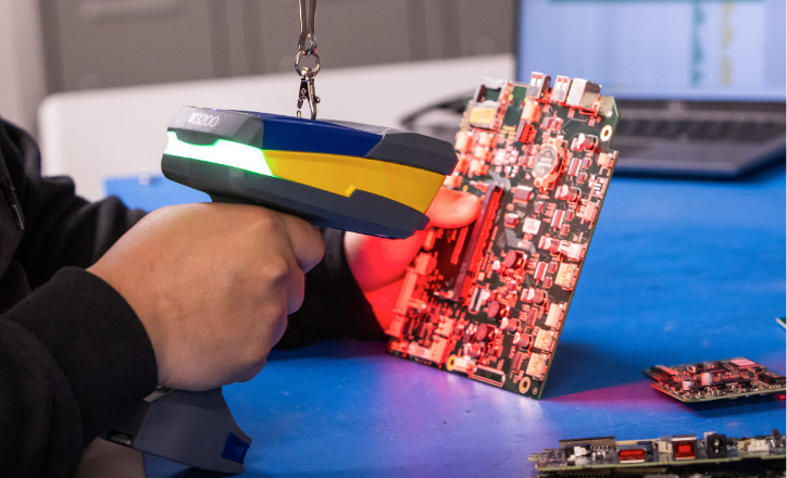 An individual uses a V3200 barcode scanner to read a Brady barcode label on a circuit board.