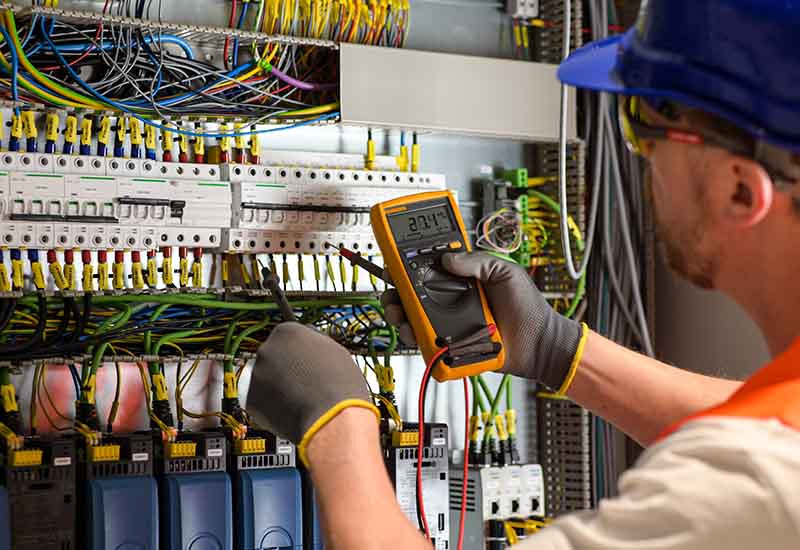 An electrical engineer inspects an electrical panel, addressing potential electrical hazards in a construction site environment.