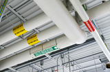 A network of pipes that adhere to valve tagging standards within a spacious industrial facility, showcasing the complexity of the building's infrastructure.
