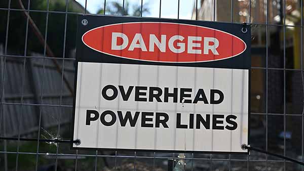 An electrical safety sign on a construction site indicating the danger for overhead powerlines.