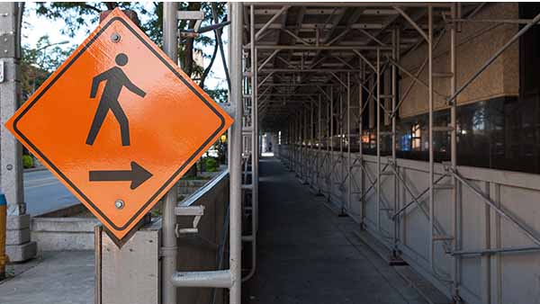 A scaffolding construction sign protects the public from covered scaffolding.