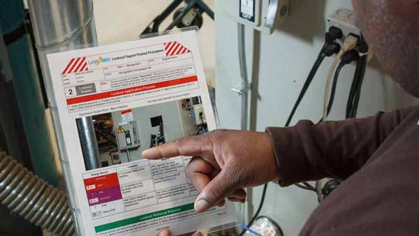 A man reviews his electrical panel lockout tagout procedure in an industrial warehouse environment.