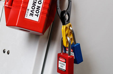 Two different colored padlocks locked to the same clamping cable lockout device.