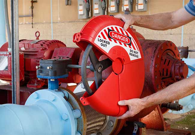 An individual applying a lockout device to a valve handle as part of their LOTOTO process.