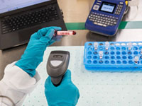 Barcode labels applied to blood vials are being scanned and recorded into pharmaceutical software.
