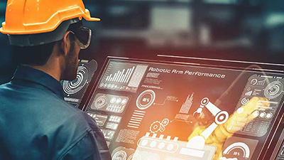 An industrial worker reviewing a screen illustrating  robotic arm performance data.